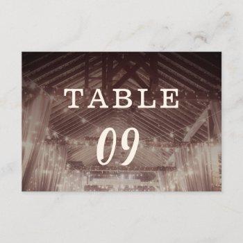 barn rafters with string lights table numbers